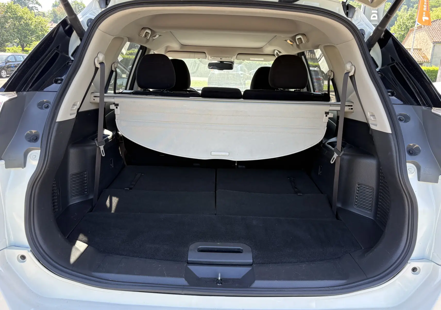 Coffre ouvert vu de l'arrière d'un Nissan X-TRAIL 1.6 DCI 130 White Edition 7 places blanc avec banquette arrière rabattue.