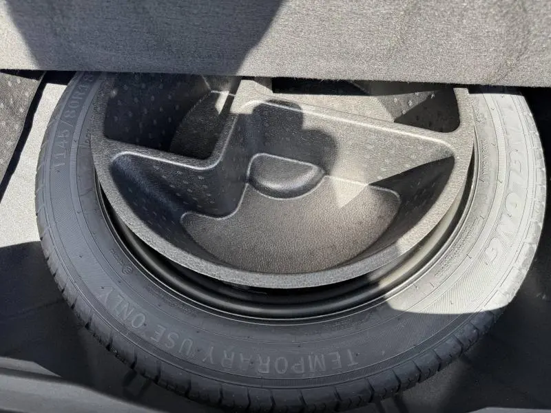 Gros plan sur la roue de secours et son rangement noir sous le coffre du Renault Rafale 1.2 E-Tech hybride 2025.