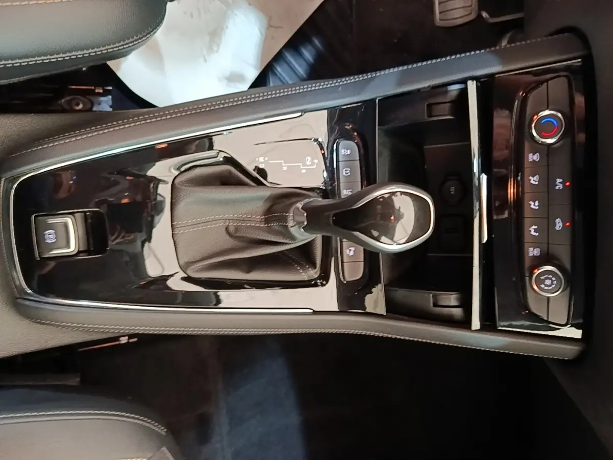 Gros plan sur la console centrale noire brillante de l'Opel Grandland X 1.5 Diesel 130 GS Line avec levier de boîte auto et commandes climatisation.