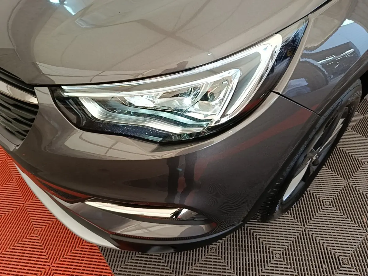Gros plan sur l'avant droit gris foncé de l'Opel Grandland X 2021, mettant en valeur le phare LED et la calandre.