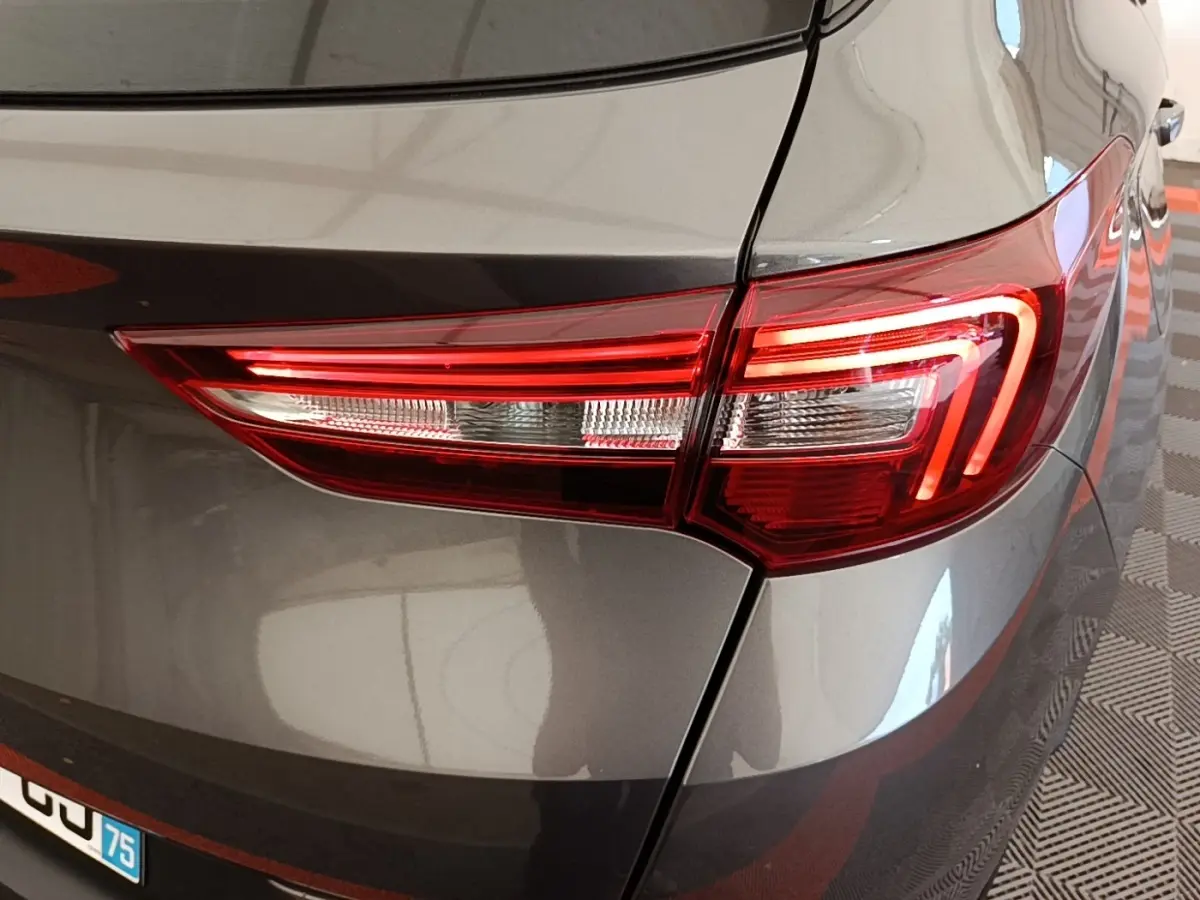 Gros plan sur le feu arrière droit rouge et blanc d’un Opel Grandland X gris foncé, vue arrière côté droit.