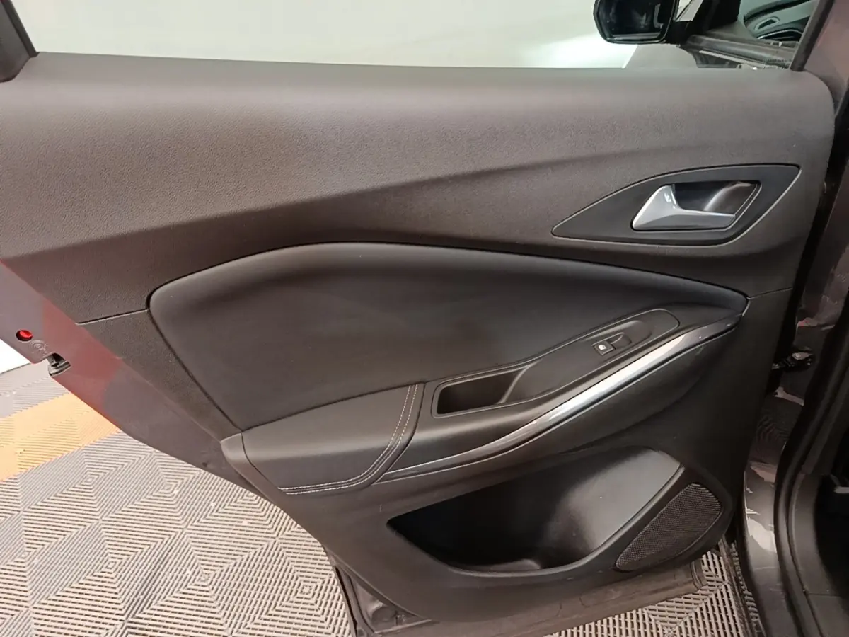 Vue intérieure de la porte avant gauche de l’Opel Grandland X gris foncé avec poignée alu et commande de fenêtre.