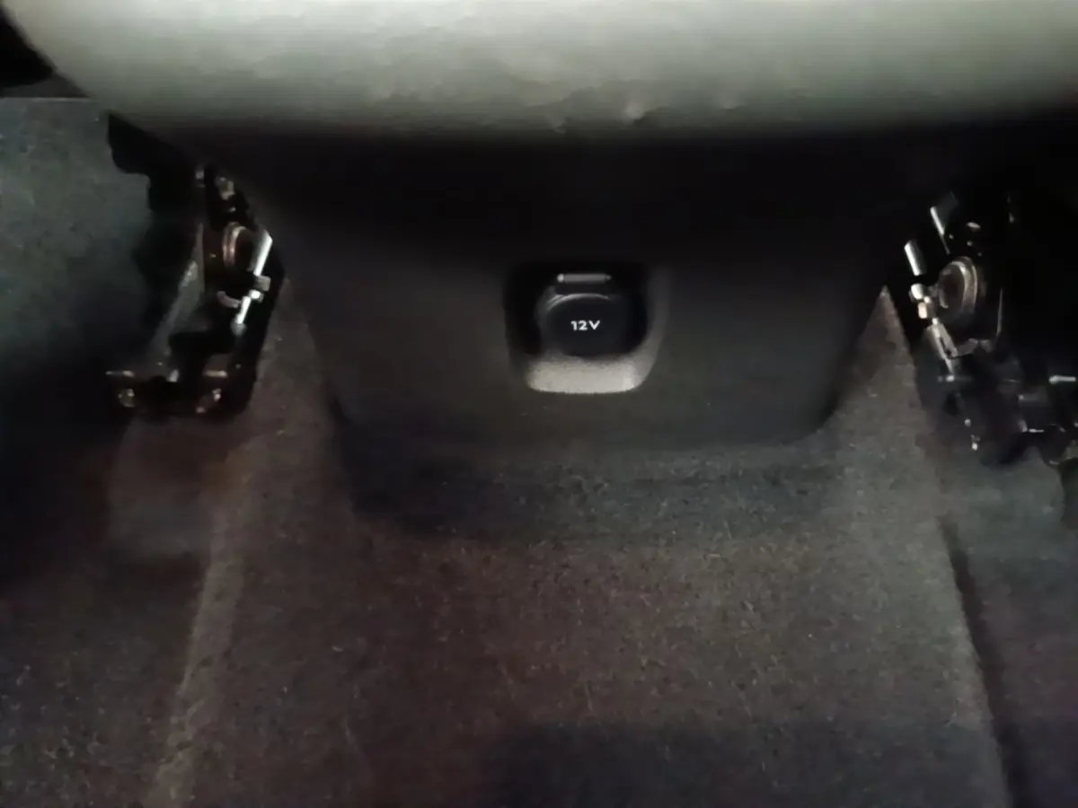 Prise 12V noire en gros plan sous la console centrale, intérieur sombre de l’Opel Grandland X gris foncé.