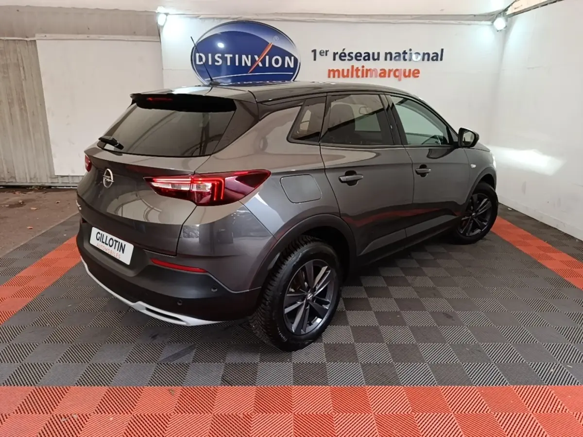 Opel Grandland X gris foncé en 3/4 arrière droit, avec jantes alliage et feux arrière LED visibles.