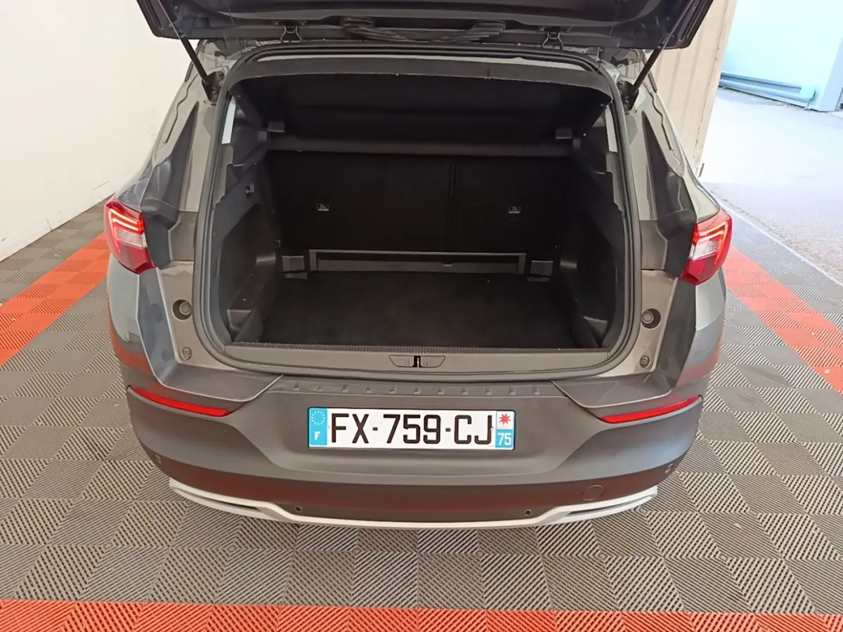 Vue arrière d'un Opel Grandland X gris foncé avec coffre ouvert, montrant l'espace de chargement vide.