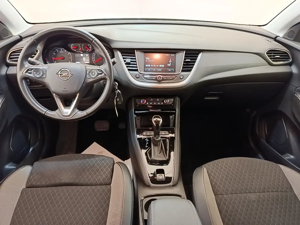 Vue intérieure avant de l'Opel Grandland X 1.5 Diesel gris, volant cuir multifonctions et console centrale avec boîte auto.