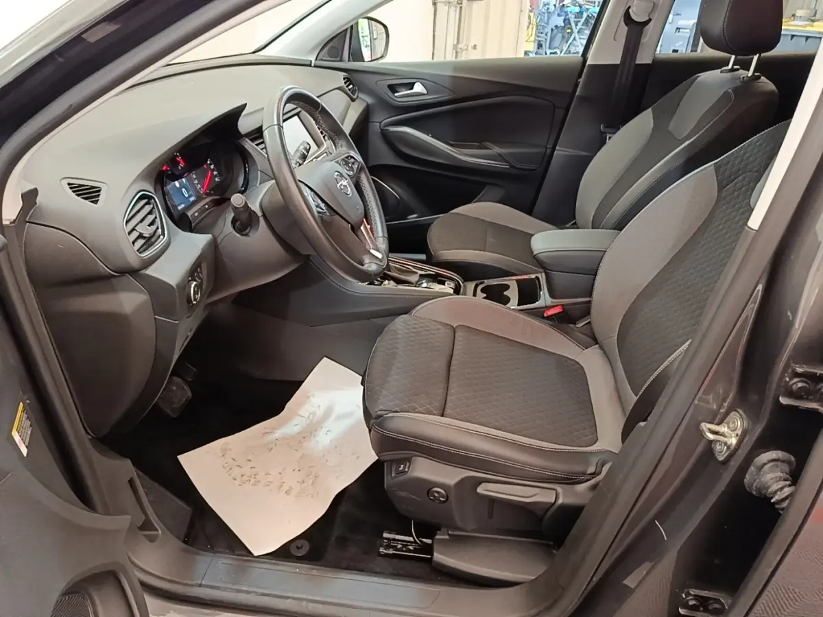 Vue intérieure côté conducteur de l'Opel Grandland X 1.5 Diesel gris foncé, volant multifonctions et sièges tissu bicolore.