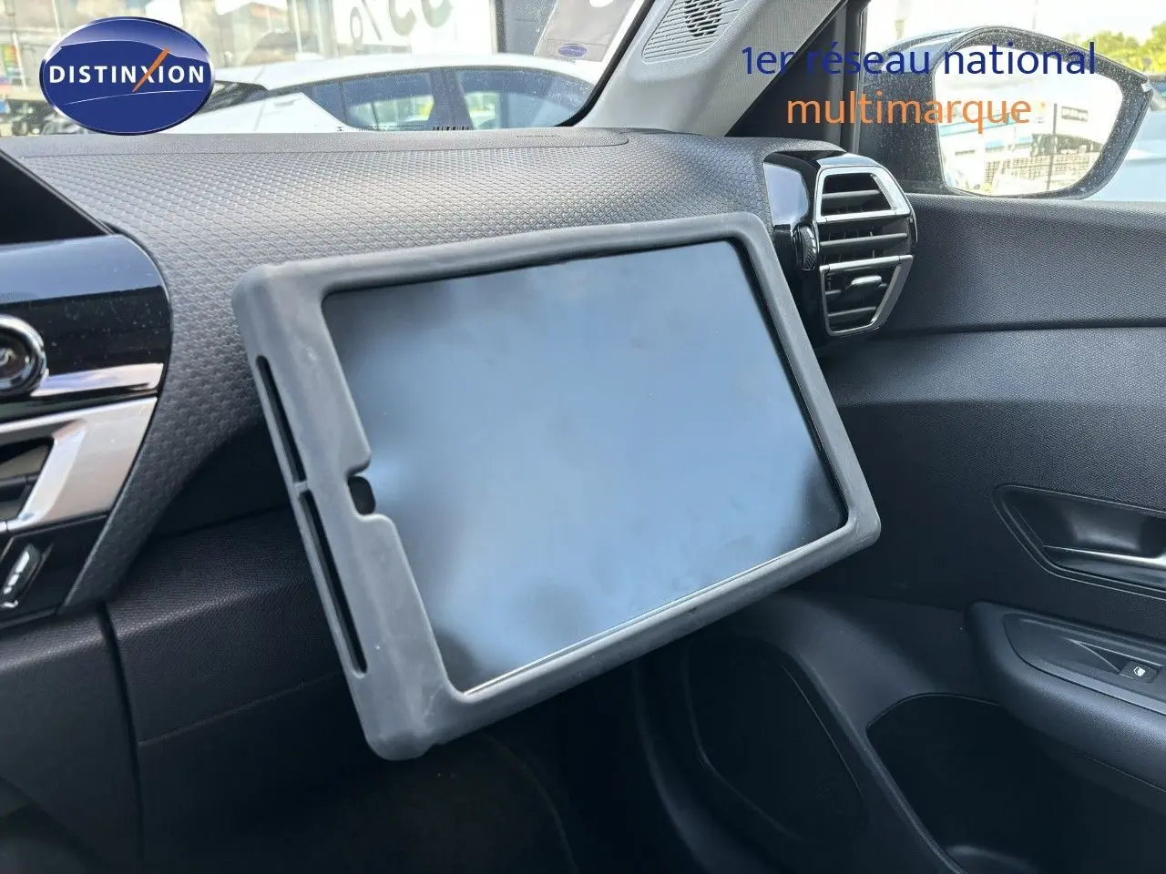 Tablette posée sur la planche de bord côté passager d'une Citroën C4 Gris Artense 2022, intérieur noir.