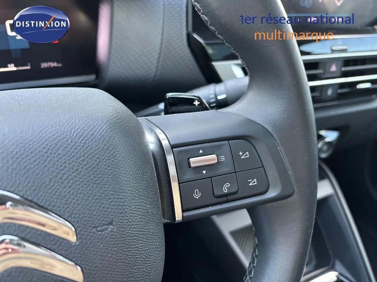 Gros plan sur le volant avec commandes intégrées du Citroën C4 gris Artense, version essence 2022, intérieur moderne.