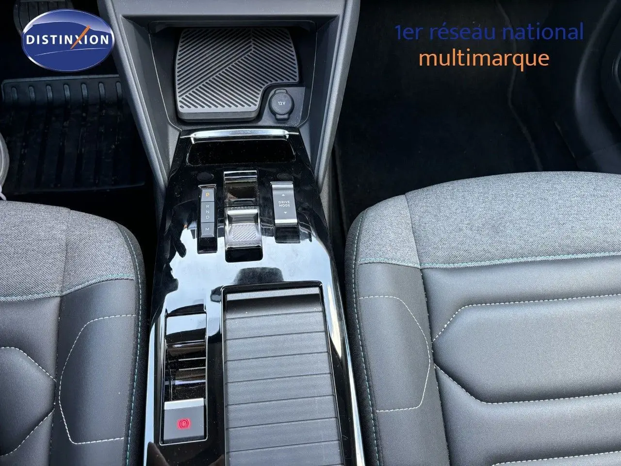 Vue rapprochée de la console centrale noire brillante et des sièges gris clair et noir du Citroën C4 Shine 2022.