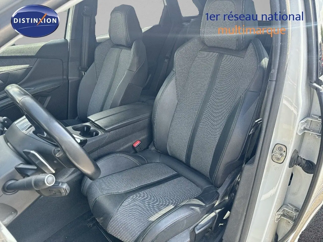 Vue intérieure côté conducteur du Peugeot 3008 blanc nacré 2022, mettant en valeur les sièges en tissu et cuir noir.