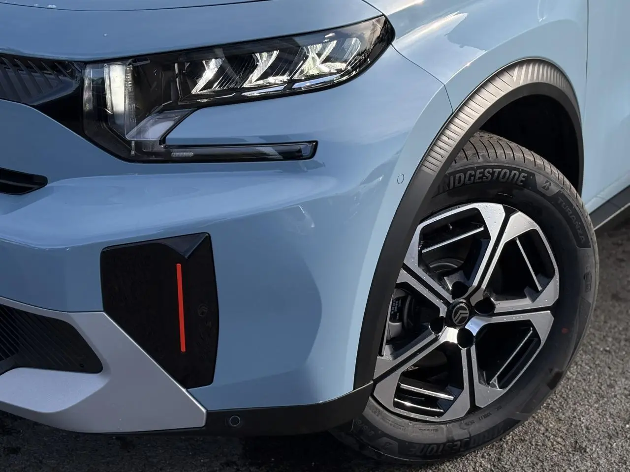 Gros plan sur l'avant droit bleu Monte Carlo du Citroën C3 Aircross Hybrid 2025 avec jante alliage diamantée et phare LED.