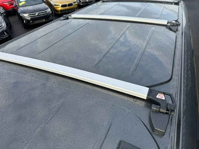 Vue rapprochée du toit gris du Volkswagen Transporter Procab 2025 avec barres de toit blanches et gouttes d'eau visibles.