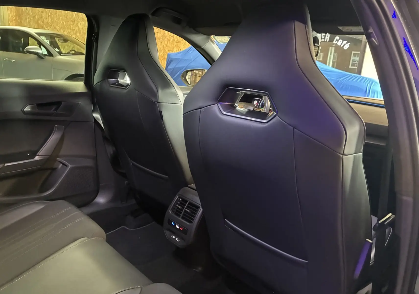 Vue intérieure arrière du CUPRA Formentor gris, montrant les sièges avant en cuir avec aérations et commandes climatisation arrière.