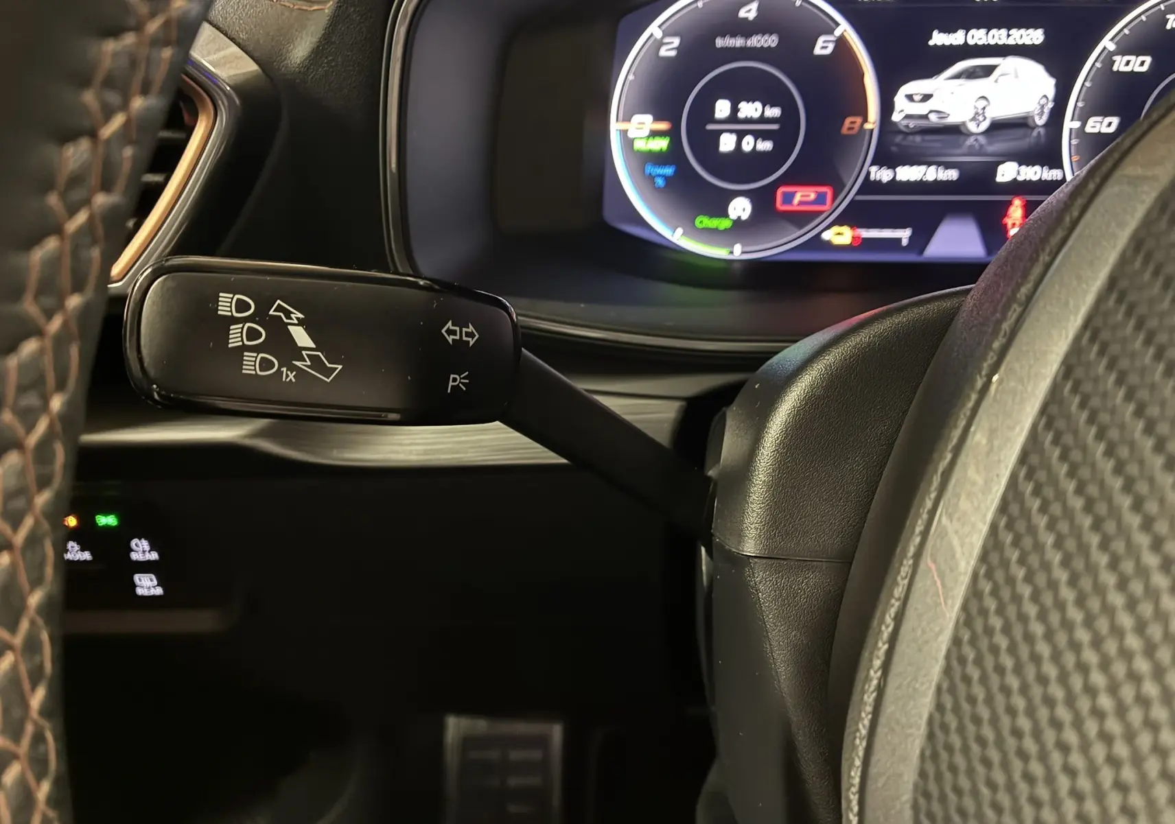 Gros plan sur la commande de clignotant à gauche du volant cuir, avec tableau de bord numérique du CUPRA Formentor gris visible.