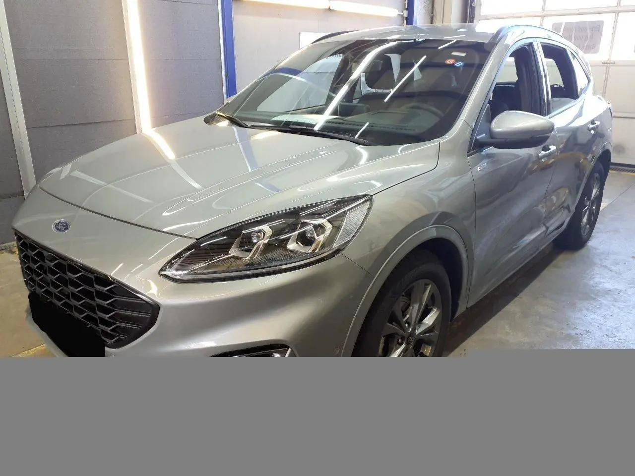 Vue 3/4 avant droite du Ford Kuga 2024 gris Solar avec calandre noire et phares Full LED visibles en intérieur.