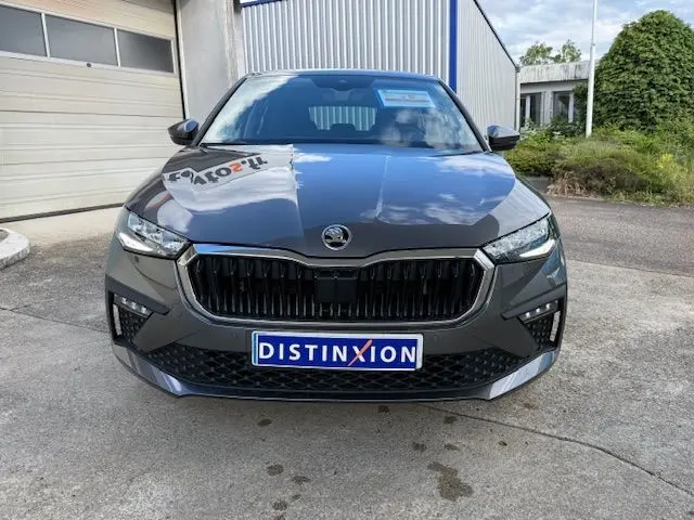 Vue frontale d'une Skoda Scala gris graphite 2025 avec calandre noire et plaque Distinxion visible.