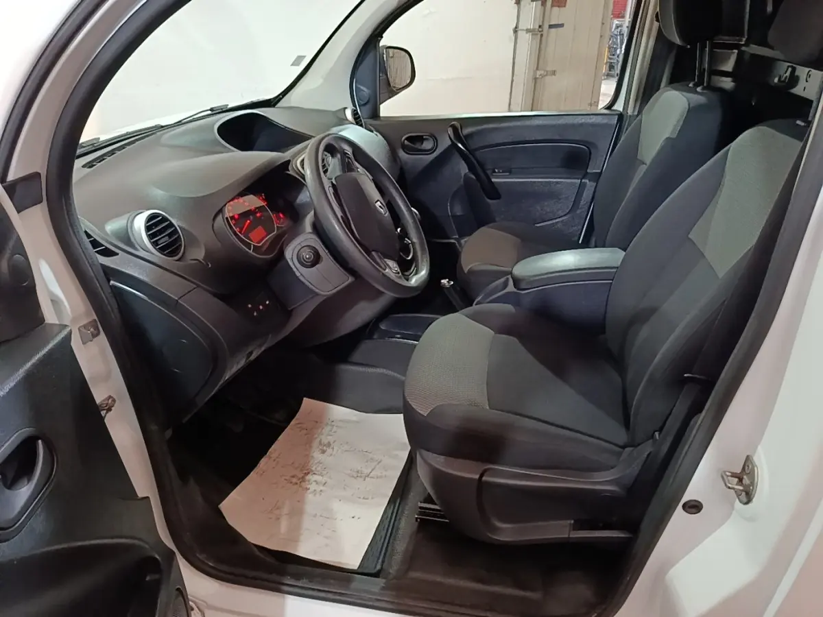Intérieur avant droit du Renault Kangoo blanc 2020, montrant sièges tissu gris et tableau de bord avec volant réglable.