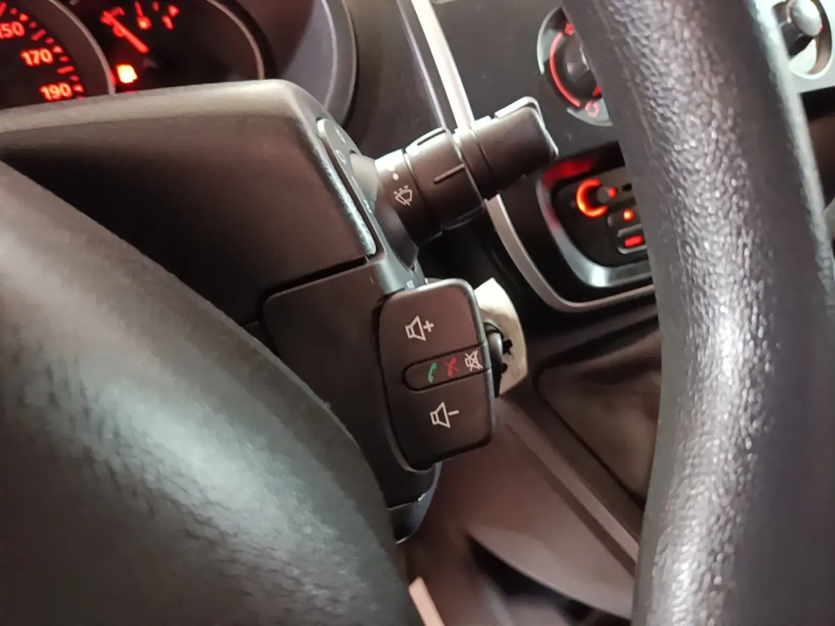 Gros plan sur le volant noir du Renault Kangoo 2020, avec commandes audio et tableau de bord partiellement visible.