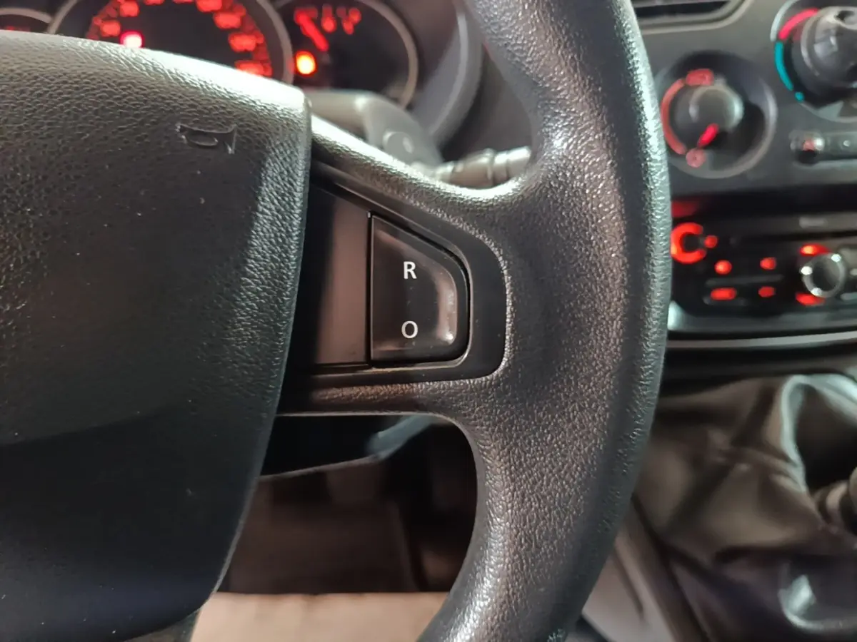 Gros plan sur le volant noir du Renault Kangoo 2020, avec tableau de bord et commandes rouges en arrière-plan.