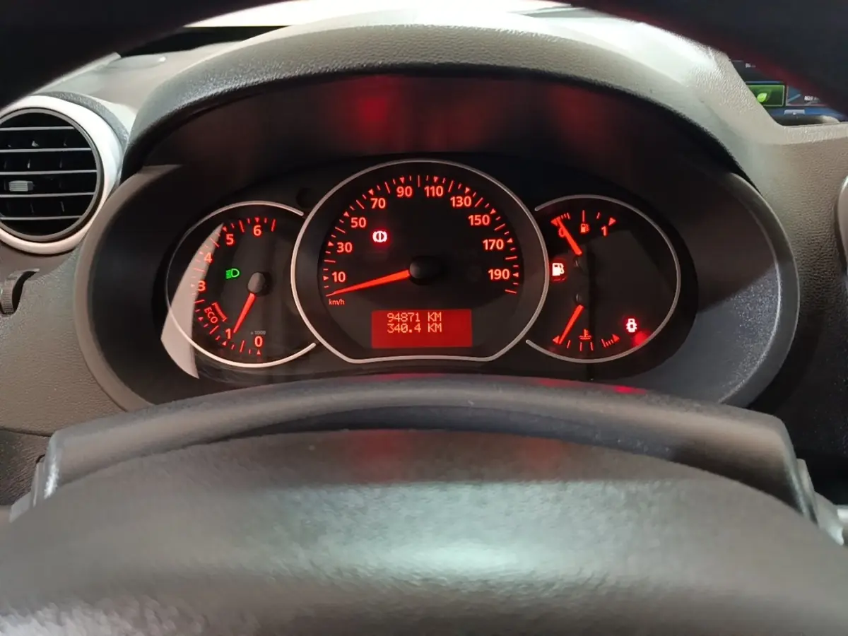 Vue rapprochée du tableau de bord du Renault Kangoo 2020, affichage rouge des compteurs derrière le volant noir.