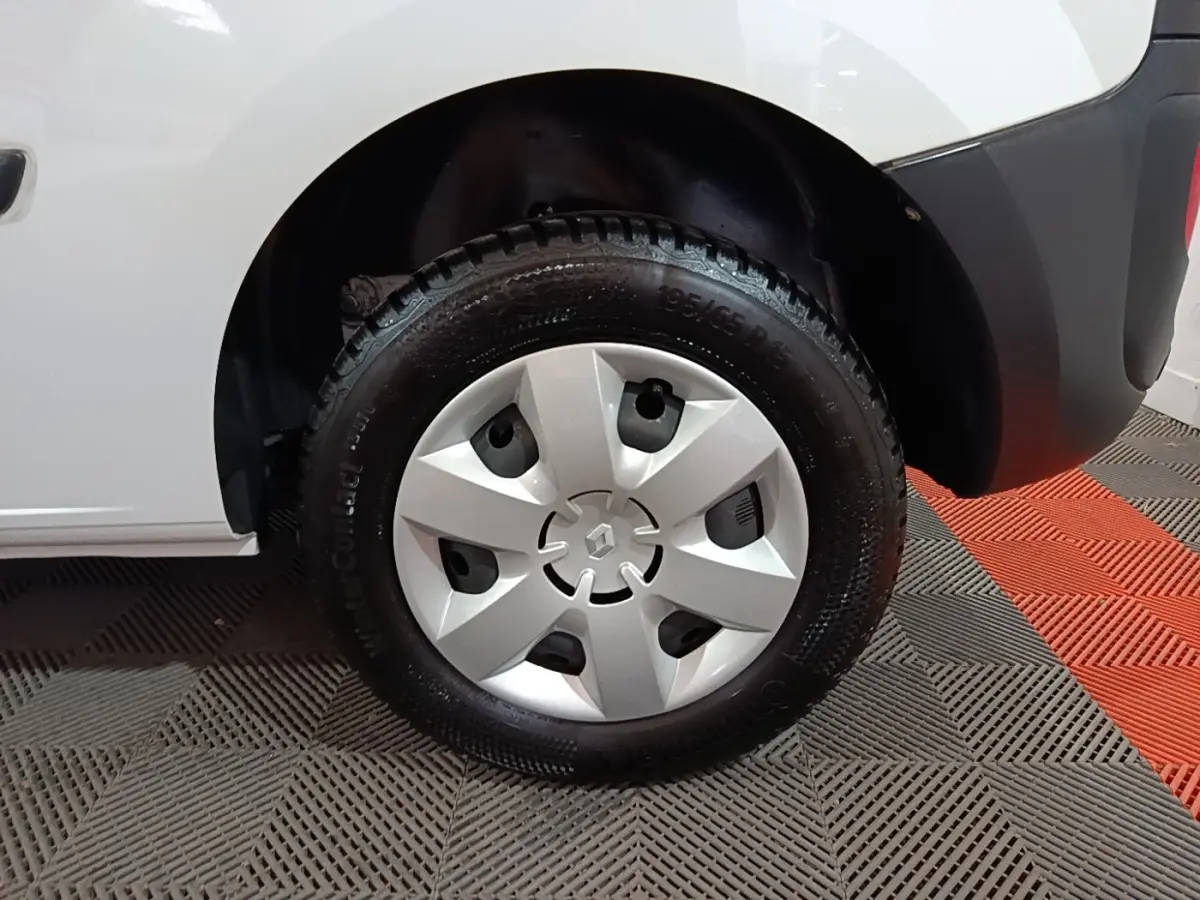 Gros plan sur la roue avant droite d’un Renault Kangoo blanc, avec enjoliveur argenté et pneu Continental.