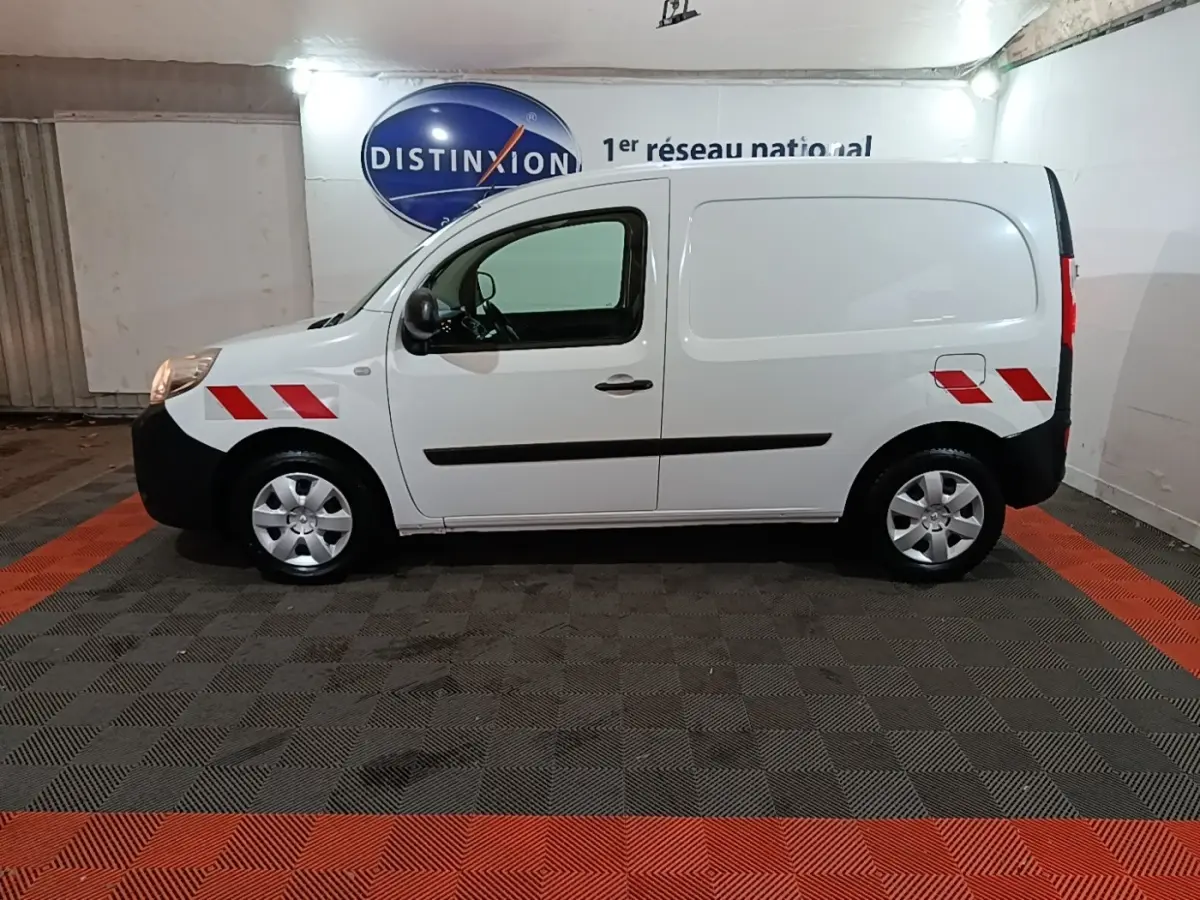 Vue de profil droit d’un Renault Kangoo blanc 2020 avec marquages rouges sur ailes avant et arrière dans un garage.
