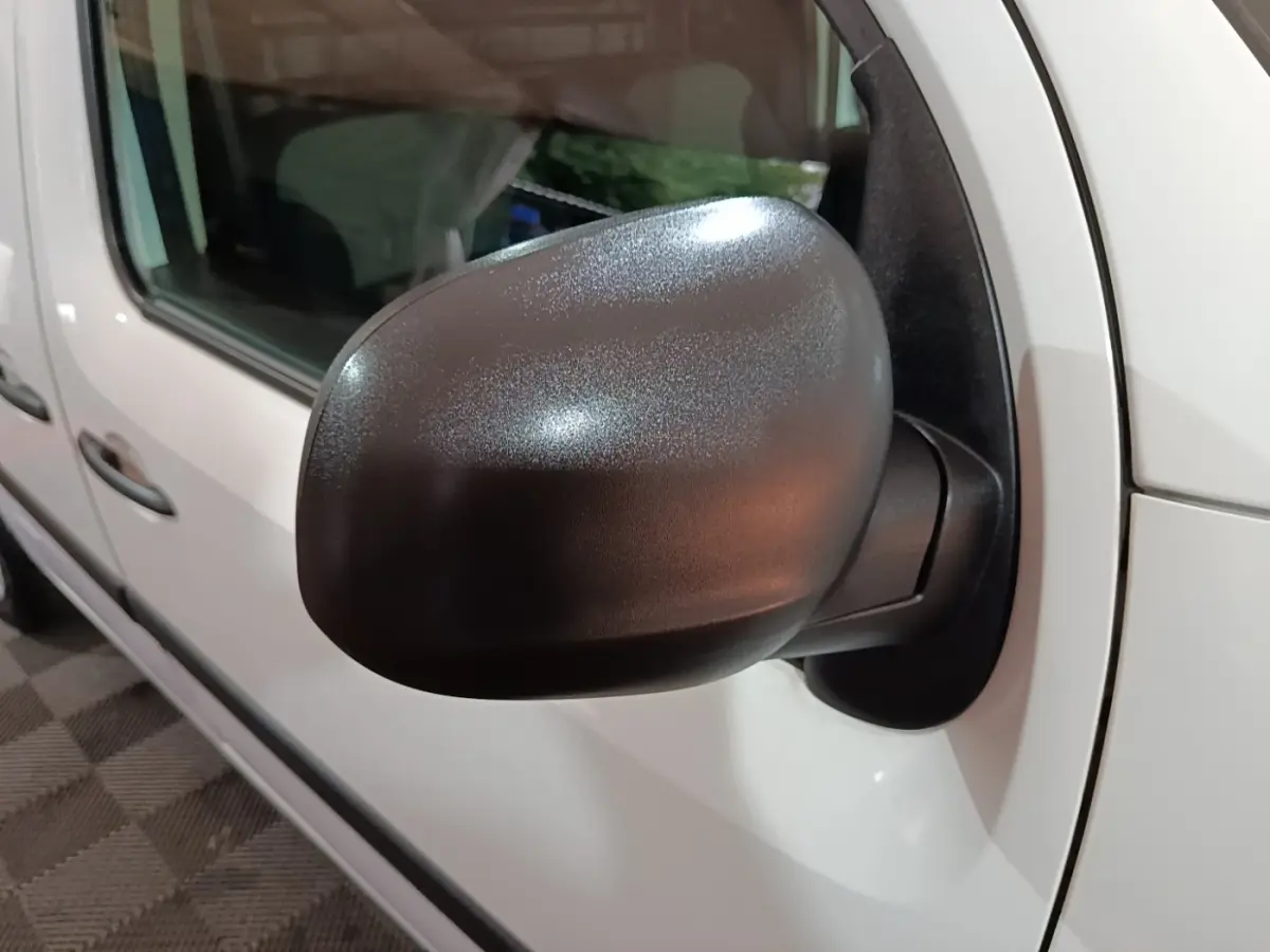 Rétroviseur noir en gros plan sur le côté gauche d’un Renault Kangoo blanc, vue latérale avant.