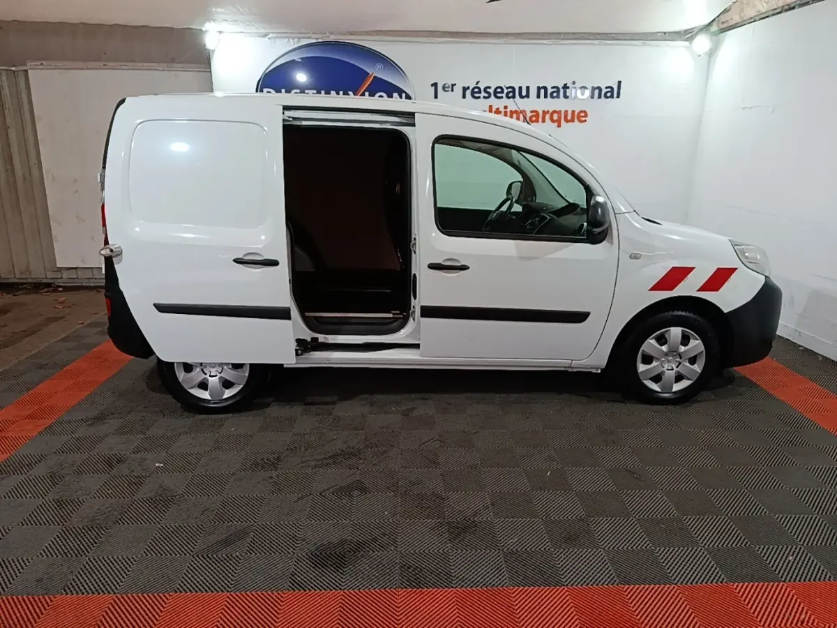 Vue de profil droit d’un Renault Kangoo blanc 2020 avec porte latérale coulissante ouverte et bandes rouges sur l’aile avant.