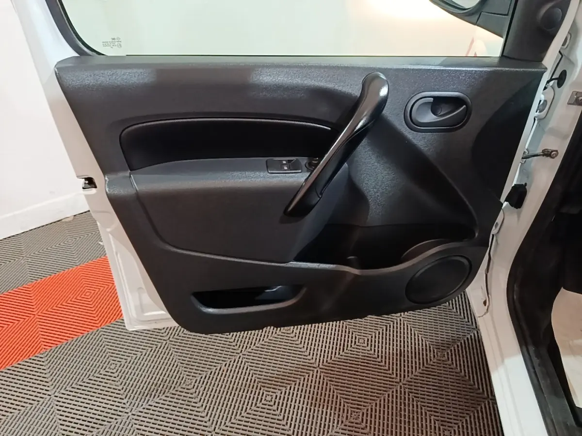 Vue rapprochée de la porte avant gauche blanche du Renault Kangoo 2020, montrant la poignée intérieure noire et les commandes de vitre.