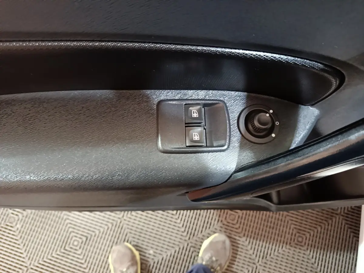 Gros plan sur les commandes de lève-vitres et réglage des rétroviseurs sur la porte côté conducteur du Renault Kangoo blanc.