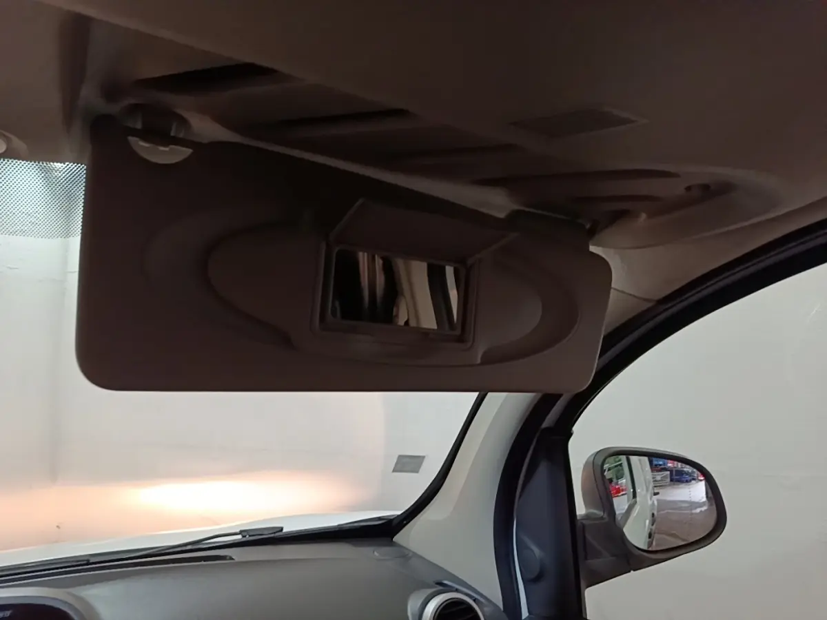 Vue intérieure du pare-soleil avec miroir ouvert côté conducteur du Renault Kangoo blanc, reflet du rétro extérieur visible.