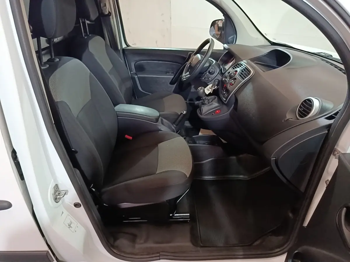 Vue intérieure côté conducteur du Renault Kangoo blanc 2020, montrant les sièges avant et le tableau de bord avec volant réglable.