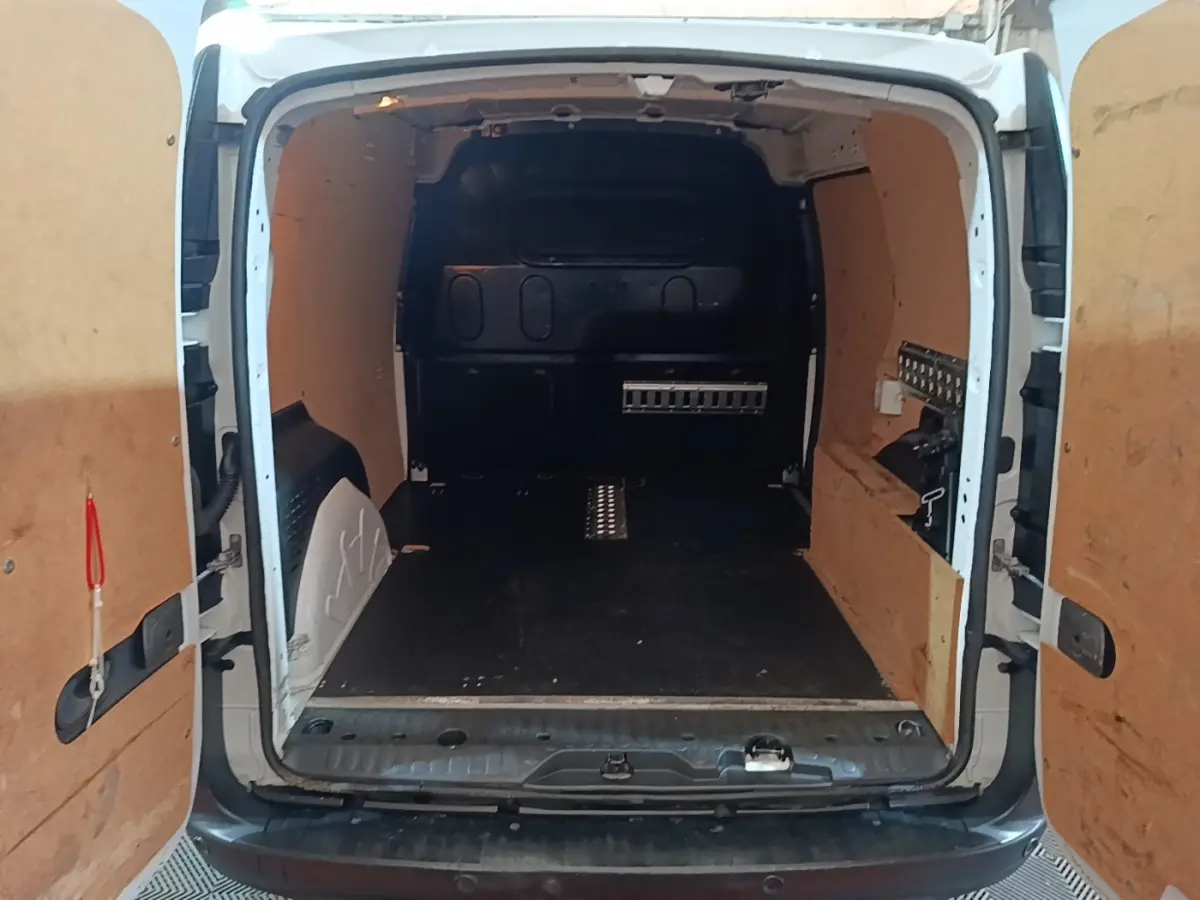 Vue arrière du Renault Kangoo blanc 2020 montrant l'espace de chargement avec cloison pleine et revêtement bois.