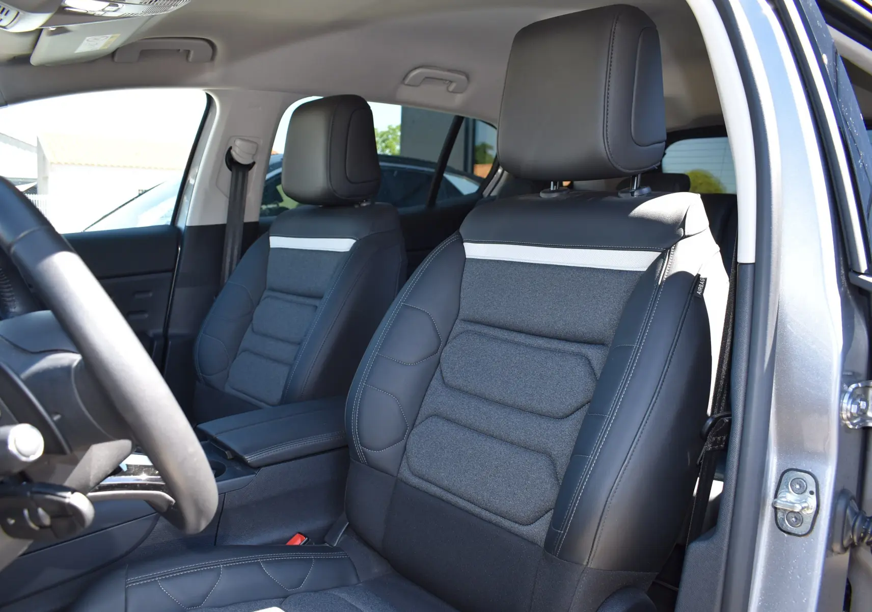 Vue intérieure côté conducteur du Citroën C5 Aircross 2024, sièges bi-matière gris et noir avec bande blanche distinctive.