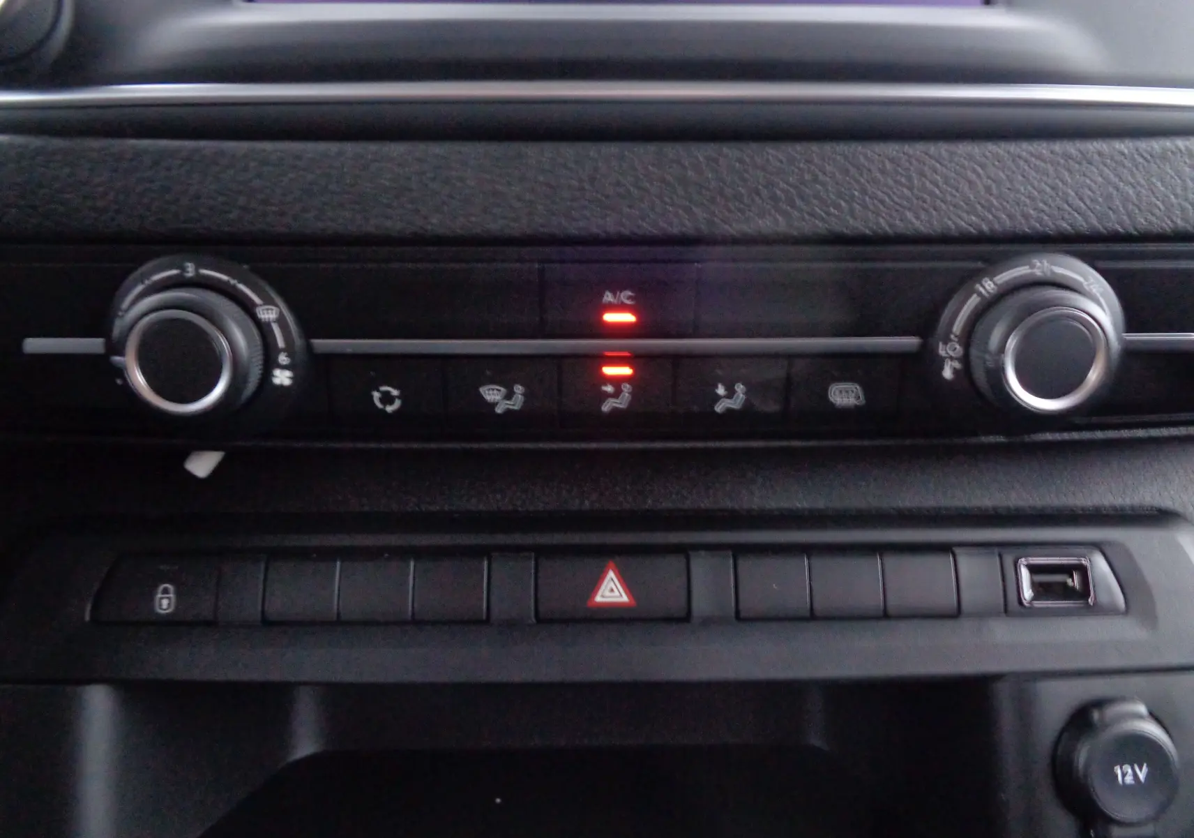 Gros plan sur la console centrale noire du Peugeot Expert Long 2023, avec commandes climatisation et boutons de fonction allumés.
