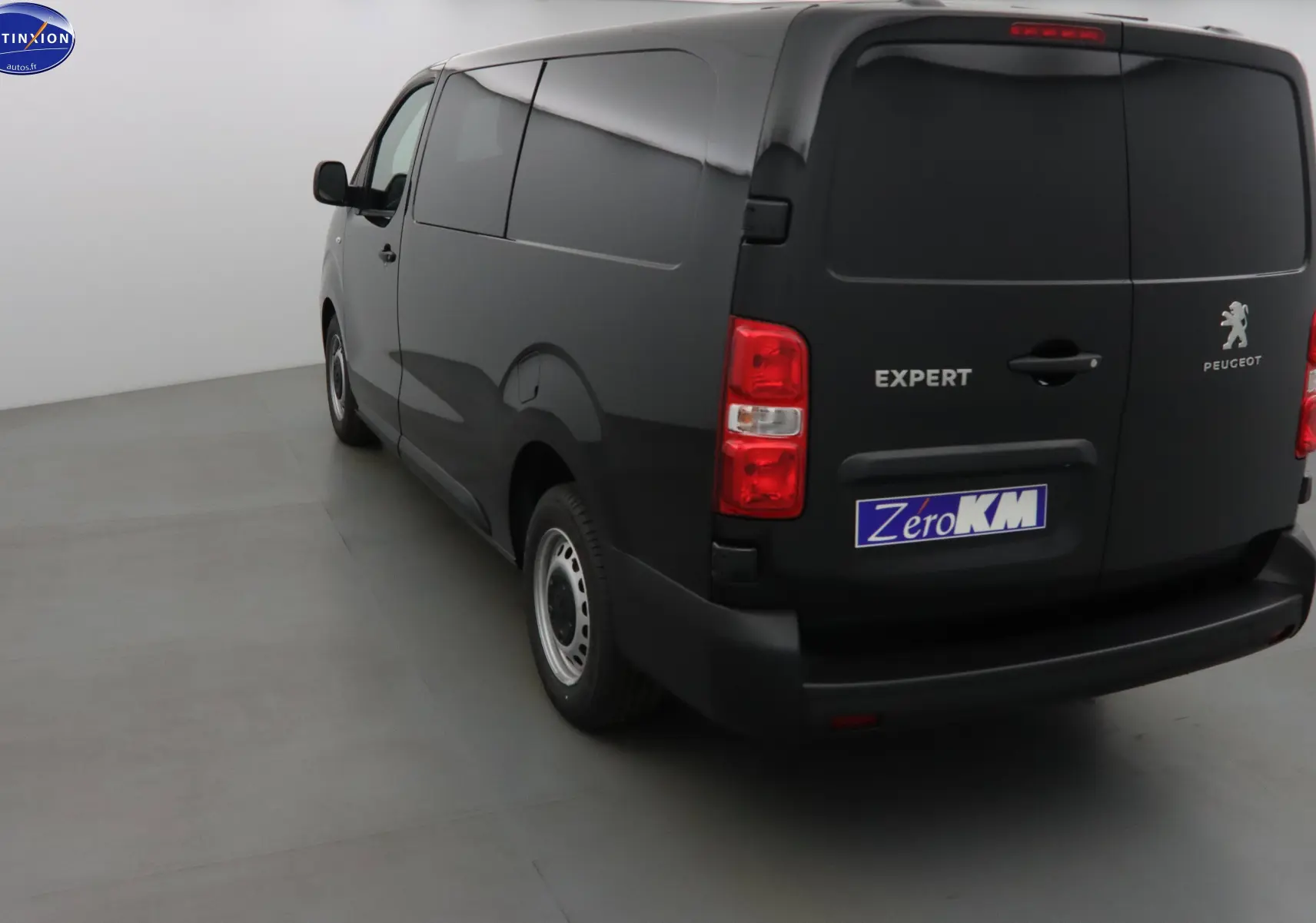 Vue 3/4 arrière gauche d'un Peugeot Expert noir perle métal, fourgon fermé avec logo et plaque Zero KM visible.
