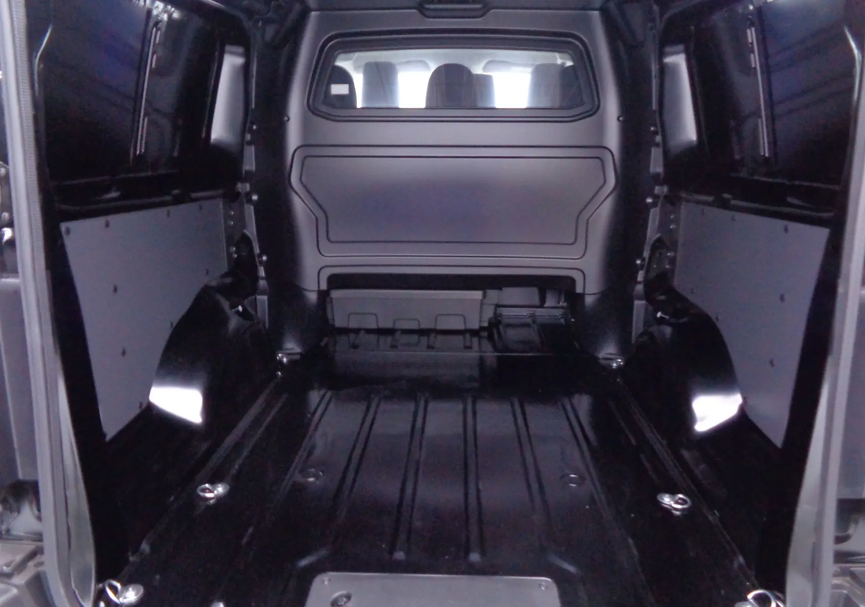 Vue intérieure de la cabine approfondie noire perle métal du Peugeot Expert Long 2023, montrant l'espace de chargement vide.