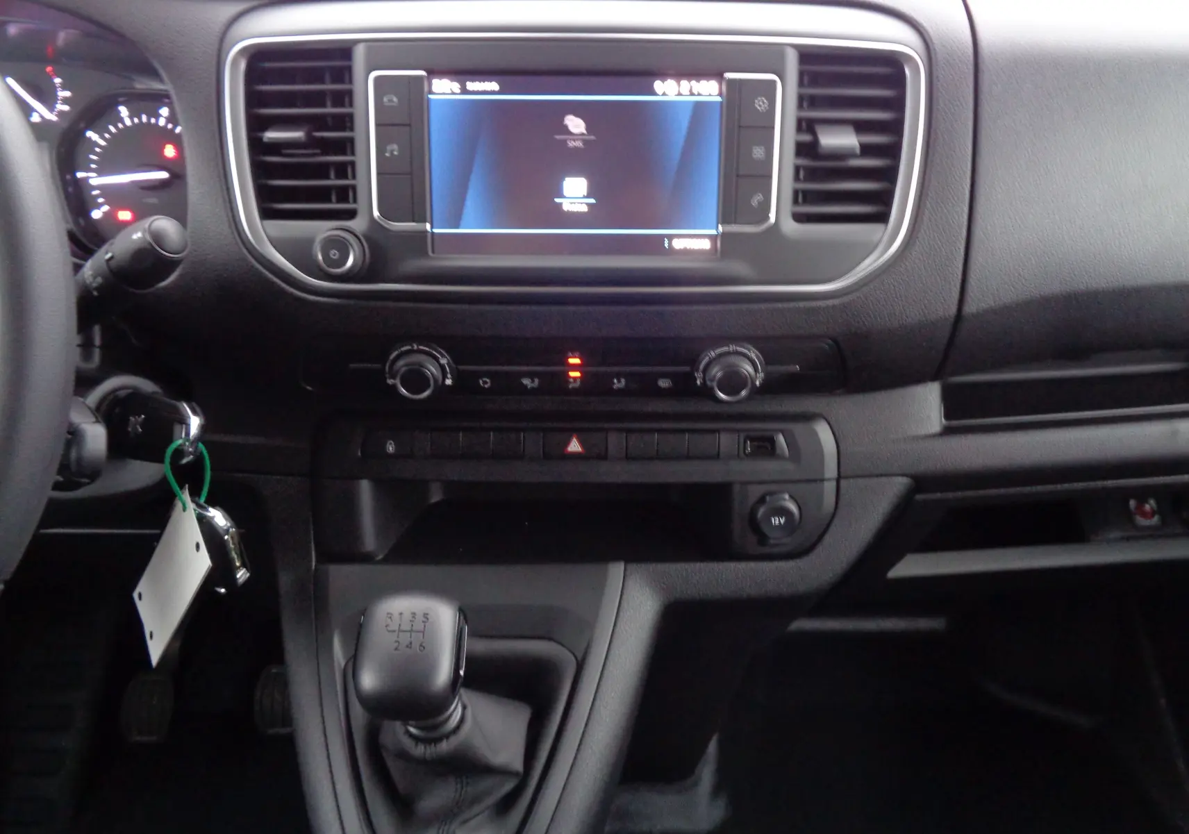 Vue intérieure du tableau de bord noir du Peugeot Expert Long 2023, avec écran tactile et levier de vitesses manuel.