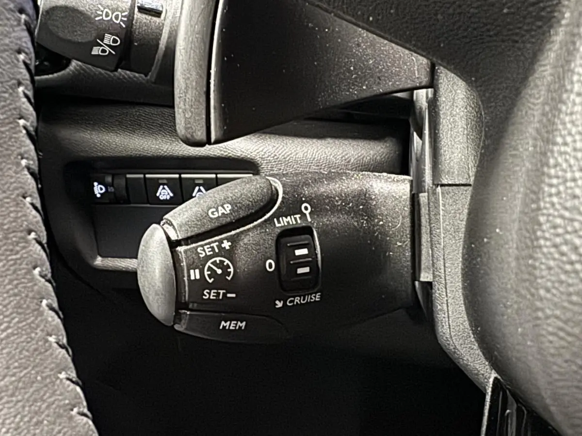 Gros plan sur la commande de régulateur de vitesse à gauche du volant du Citroën C5 Aircross noir 2022.