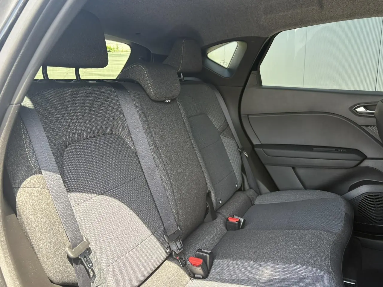 Vue latérale droite de la banquette arrière noire du Renault Captur 2025 avec ceintures et appuie-têtes intégrés.
