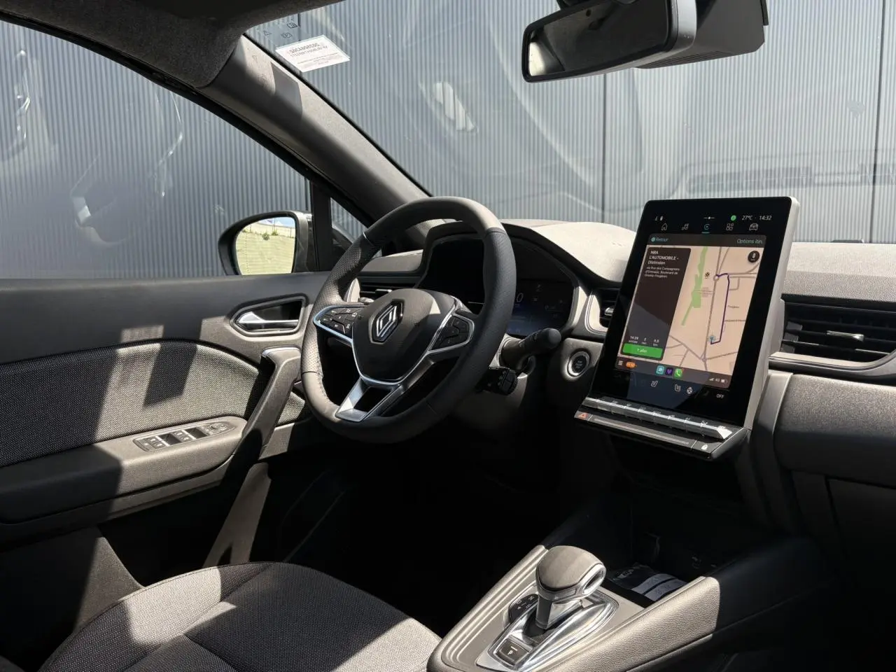 Intérieur noir du Renault Captur 2025 vu côté conducteur, avec volant multifonctions et écran tactile vertical affichant la navigation.