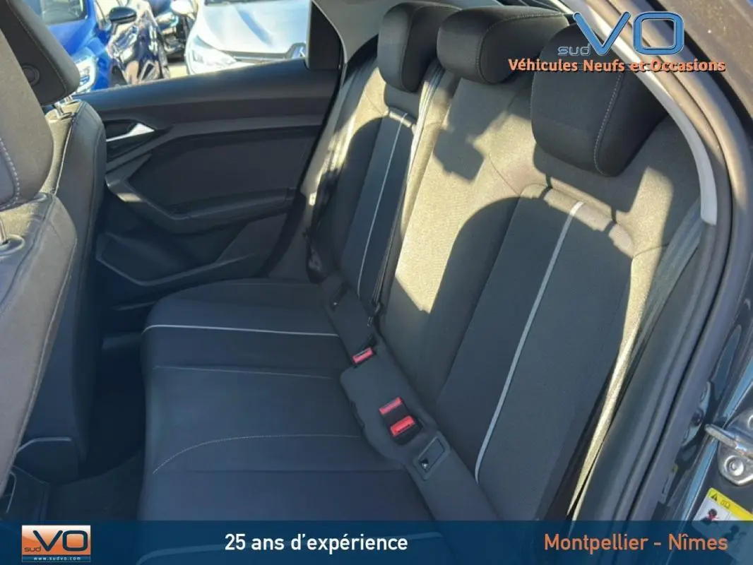 Vue intérieure des sièges arrière noirs avec surpiqûres claires de l'Audi A1 Sportback gris foncé, porte ouverte côté droit.