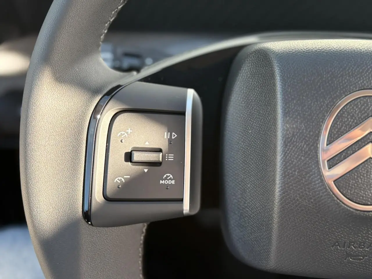 Gros plan sur les commandes multifonctions à gauche du volant noir du Citroën C3 Aircross Hybrid 2025.