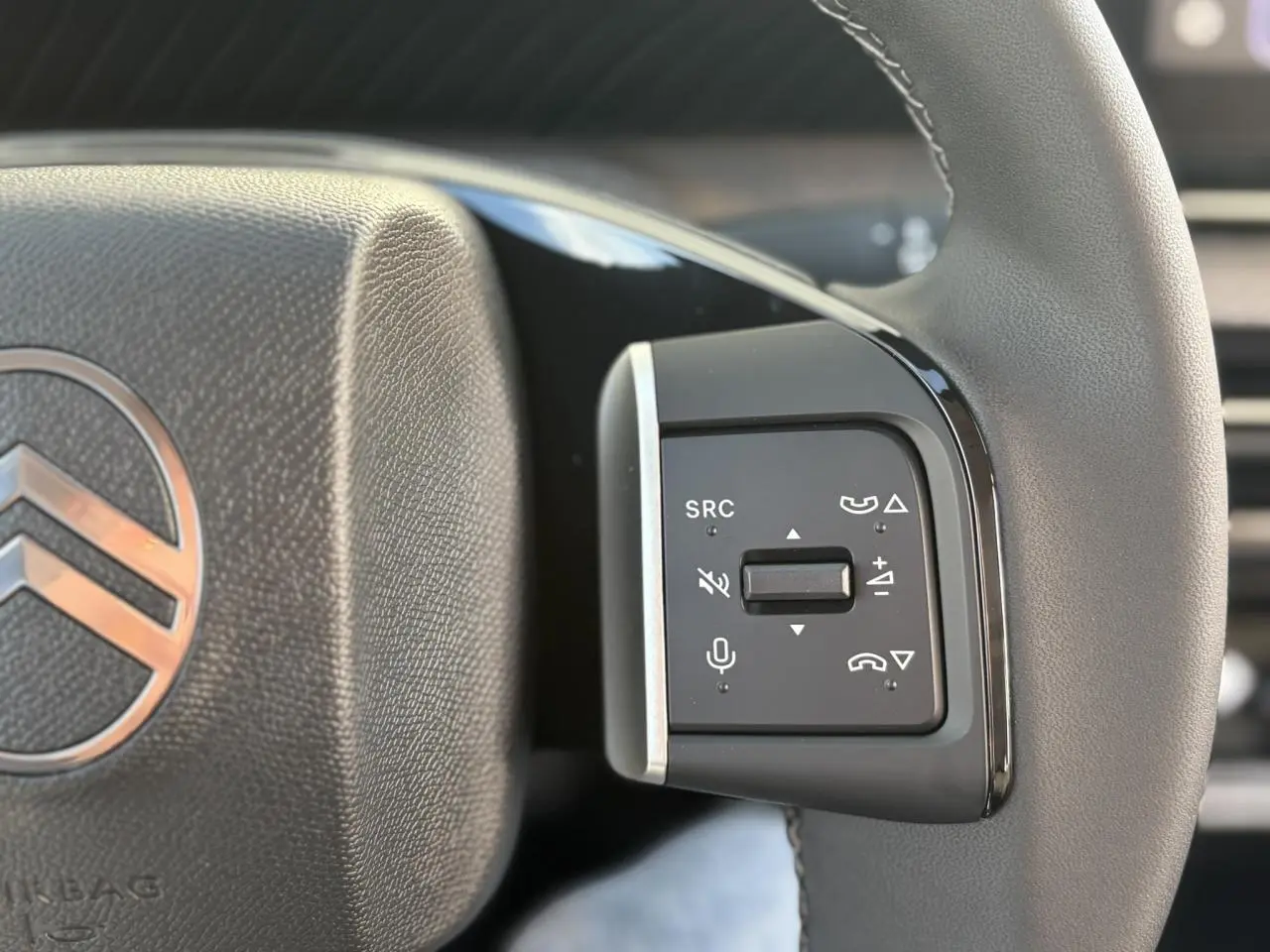 Gros plan sur les commandes multifonctions à droite du volant gris du Citroën C3 Aircross Hybrid 2025.