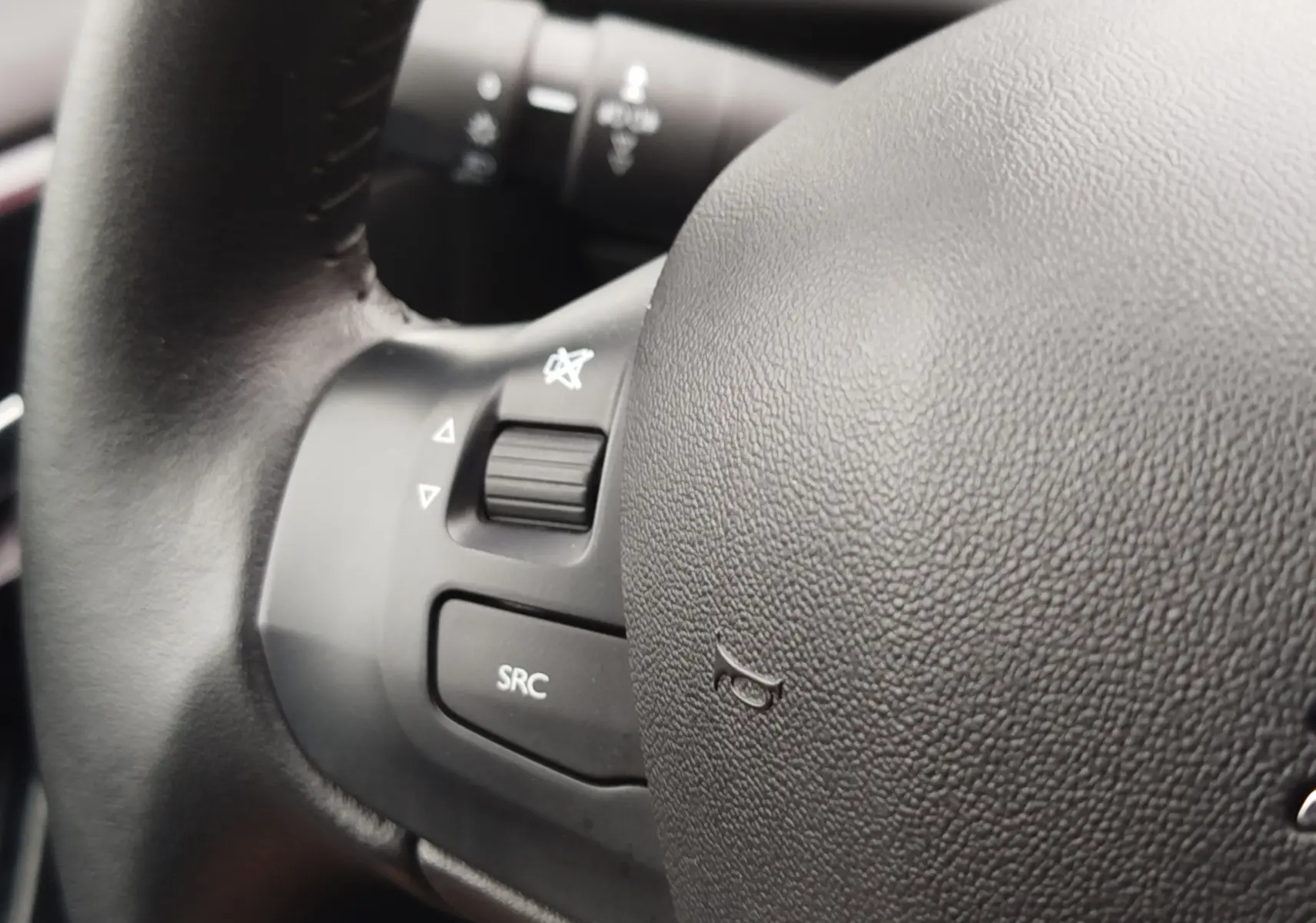 Gros plan sur le volant noir de la Peugeot 208 2019, montrant les commandes audio et le bouton SRC.