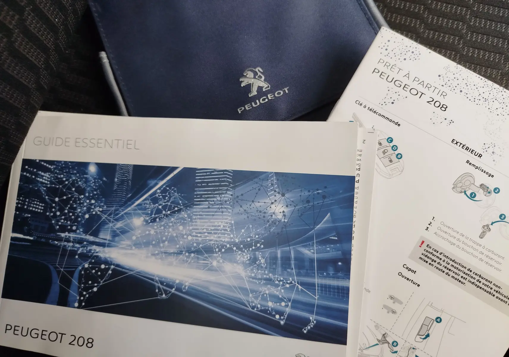 Image montrant des documents et un étui bleu Peugeot, sans véhicule visible.