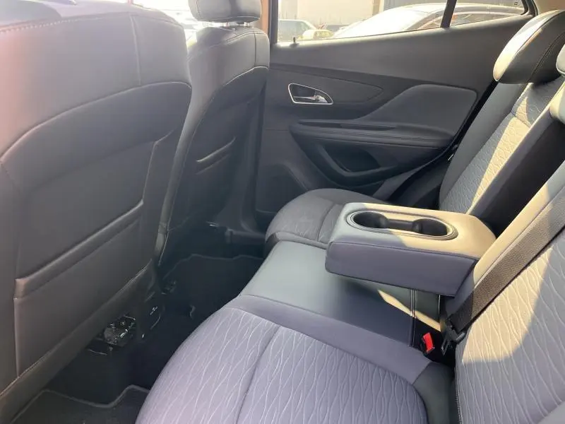 Vue intérieure arrière côté droit de l’Opel Mokka 2015, sièges tissu bicolore avec accoudoir central et porte-gobelets.