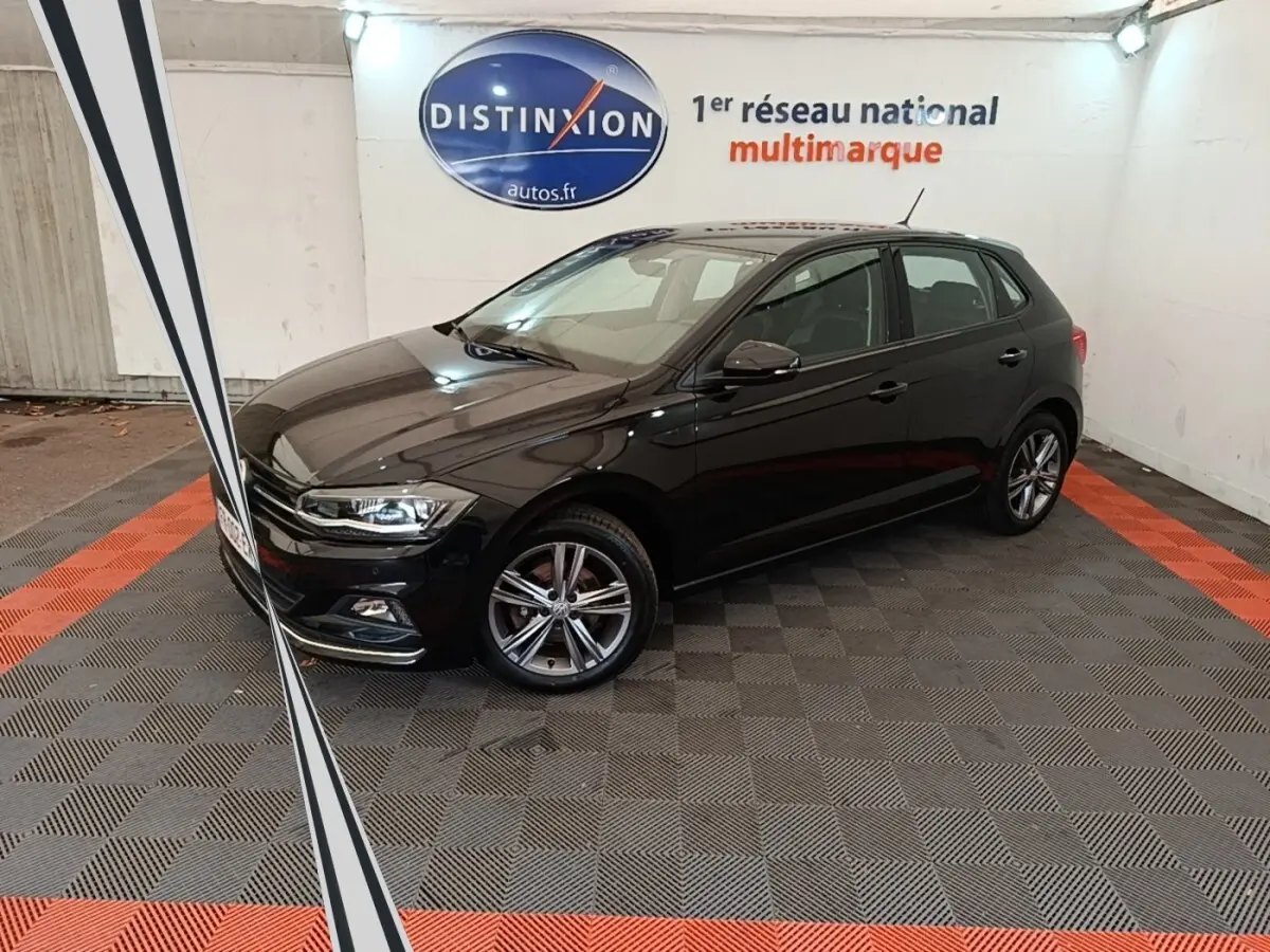 Volkswagen Polo noire 2020 vue 3/4 avant droit en intérieur avec jantes alliage et phares LED allumés.