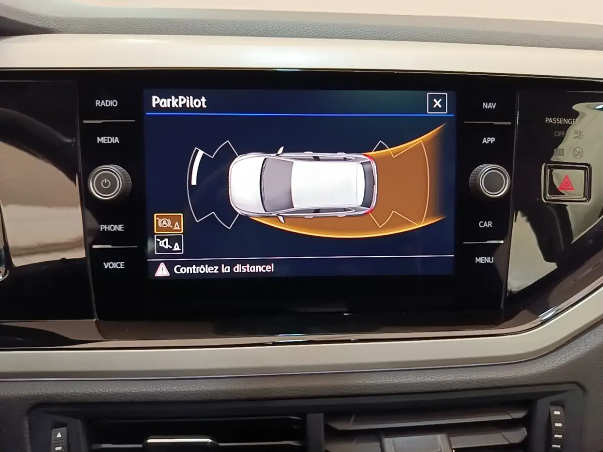 Écran tactile intérieur affichant l'aide au stationnement ParkPilot dans une Volkswagen Polo noire de 2020.
